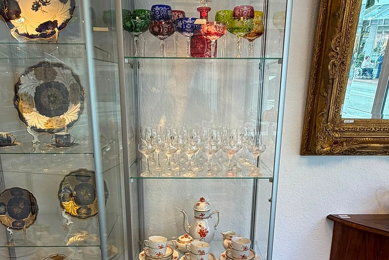 Zwei beleuchtete Glasvitrinen mit antikem Porzellan, Goldrand-Tellern und böhmischen Kristallgläsern