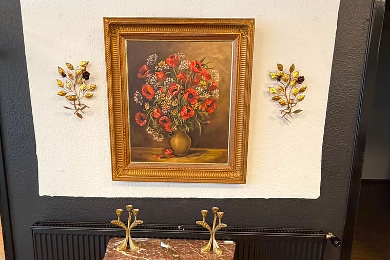 Antikes Blumenstillleben im Goldrahmen zwischen vergoldeten Wandleuchtern über einer Marmor-Kommode
